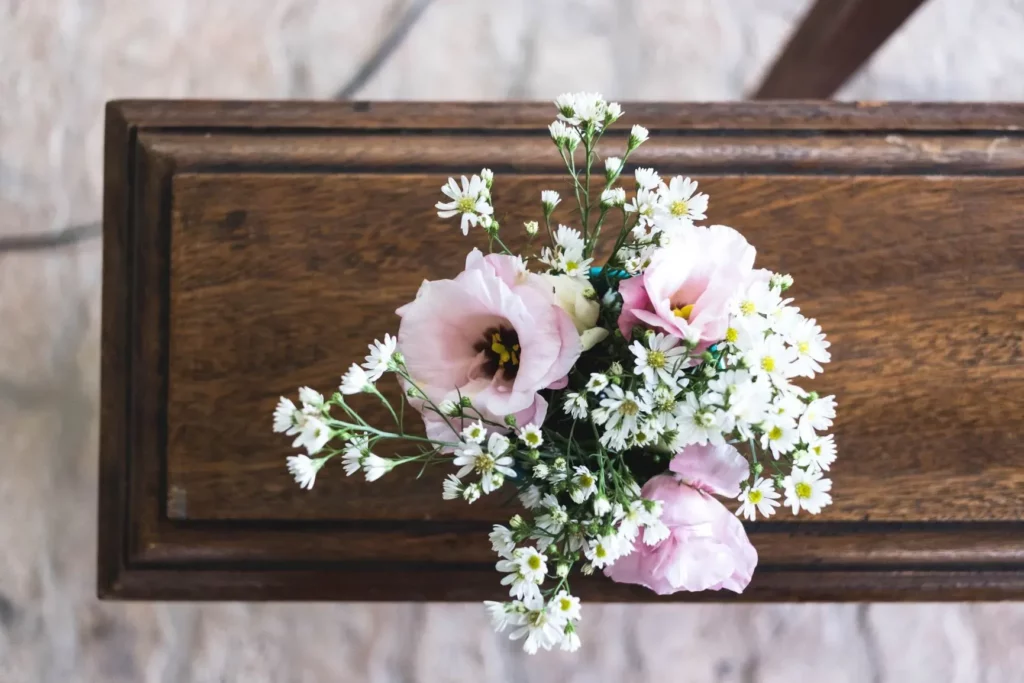 Petit bouquet de fleurs roses et blanches posé sur un cercueil en bois.