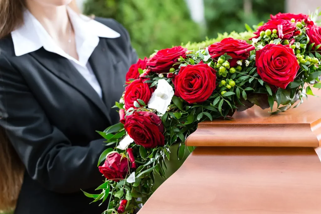 Conseillère funéraire disposant une gerbe de roses rouges sur un cercueil.