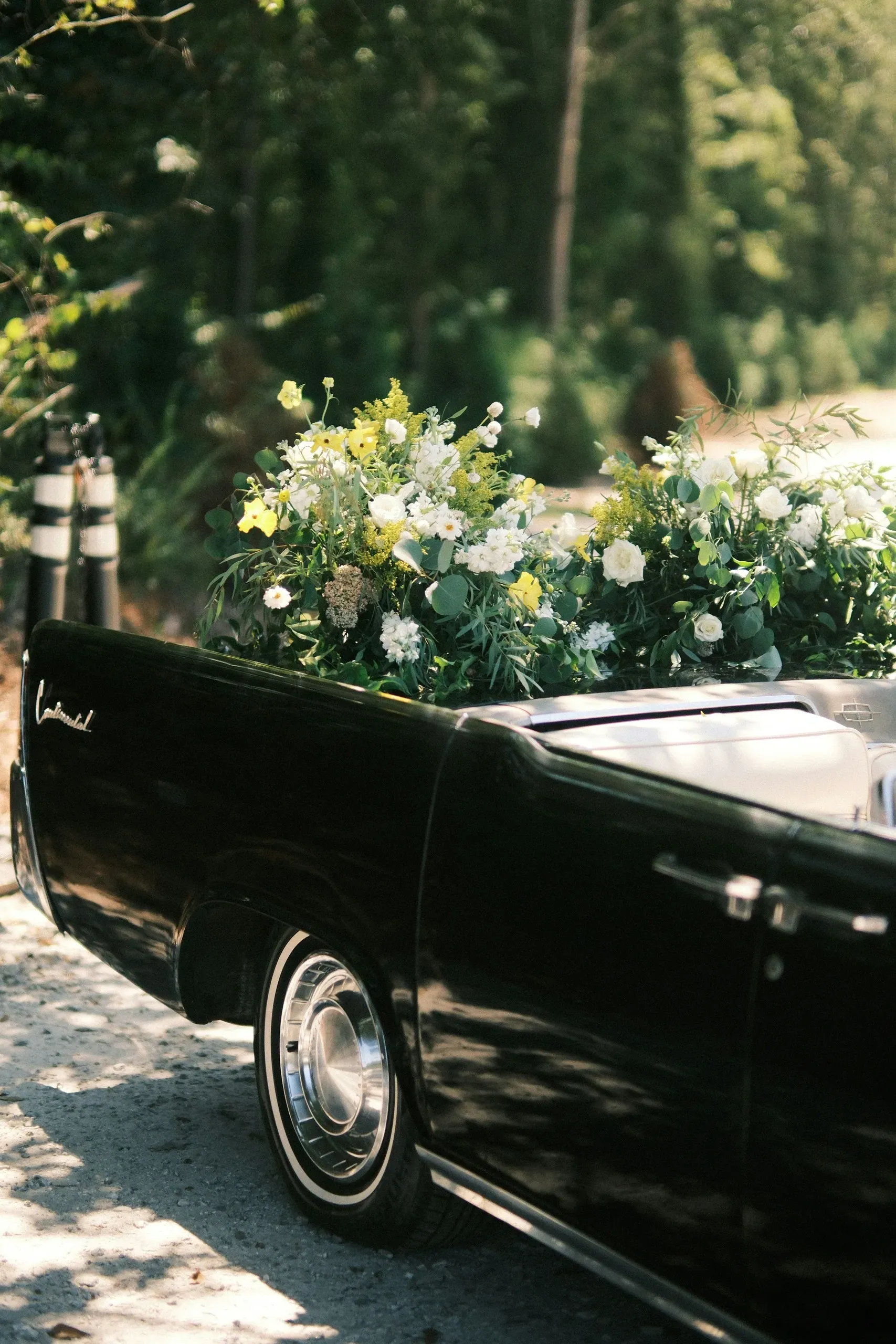 Voiture ancienne noire transportant des compositions florales pour des obsèques.